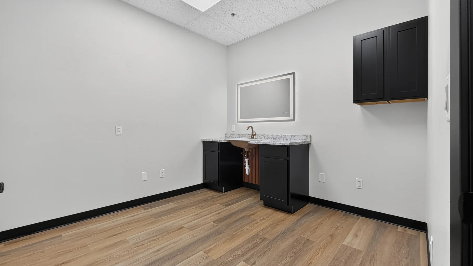 Private studio with counter, sink, wall mirror, and black storage cabinets