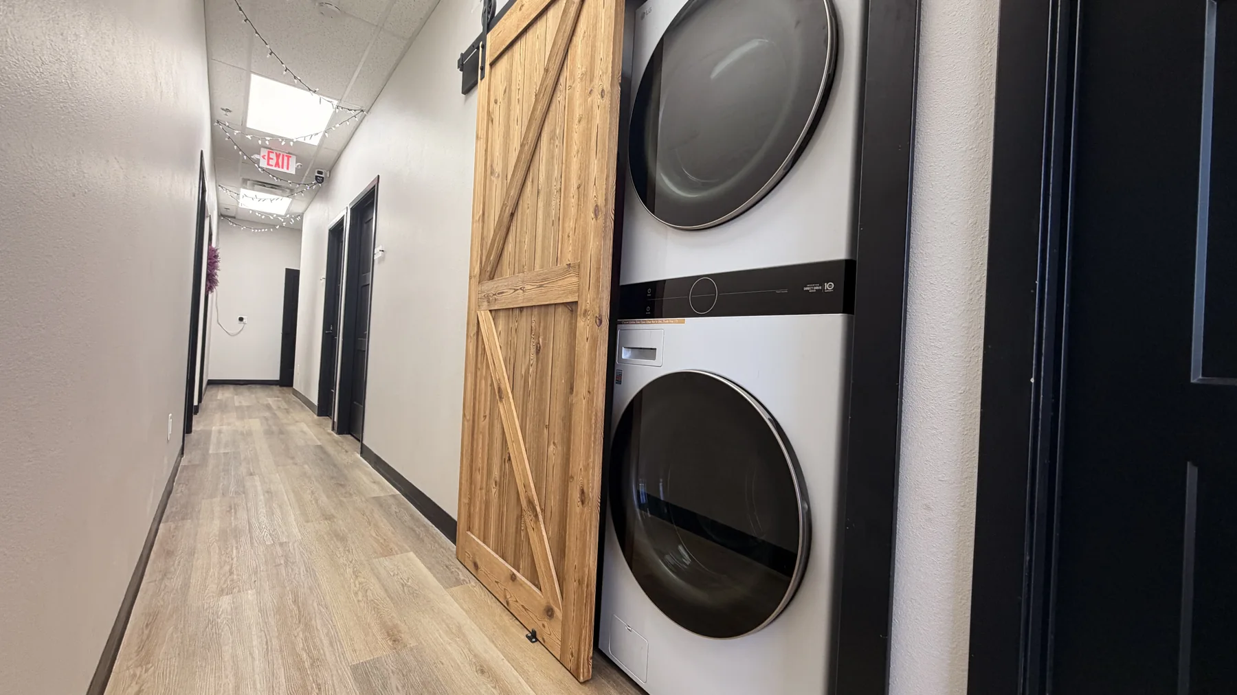 Stacked washer and dryer behind a sliding wood door in The Beauty Spot hallway